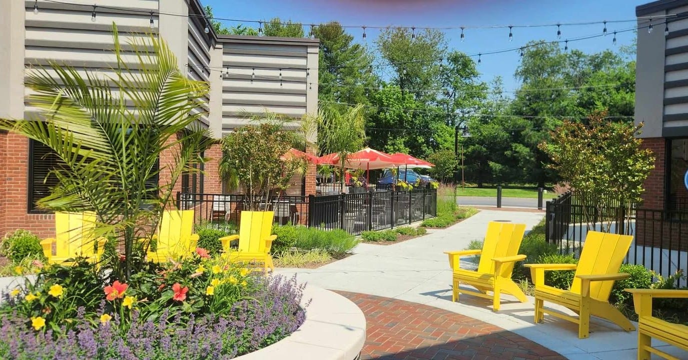 Colorful outdoor patio with yellow chairs and flowers.
